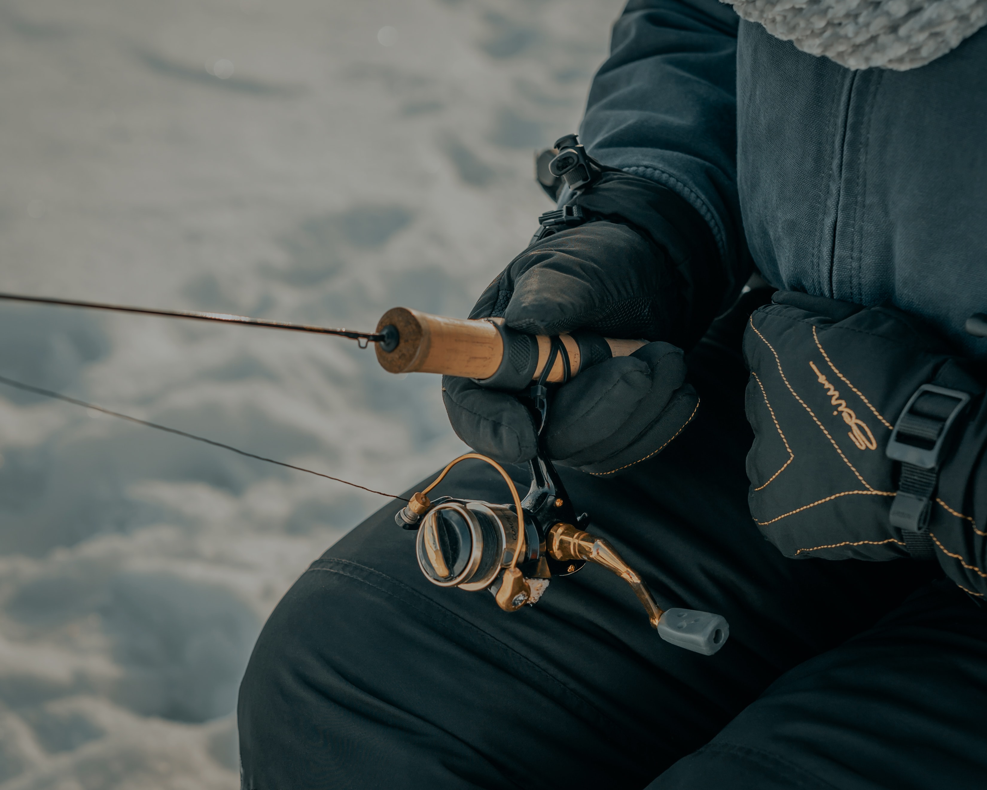 Close-up of an ice fishing rod and reel in gloved hands