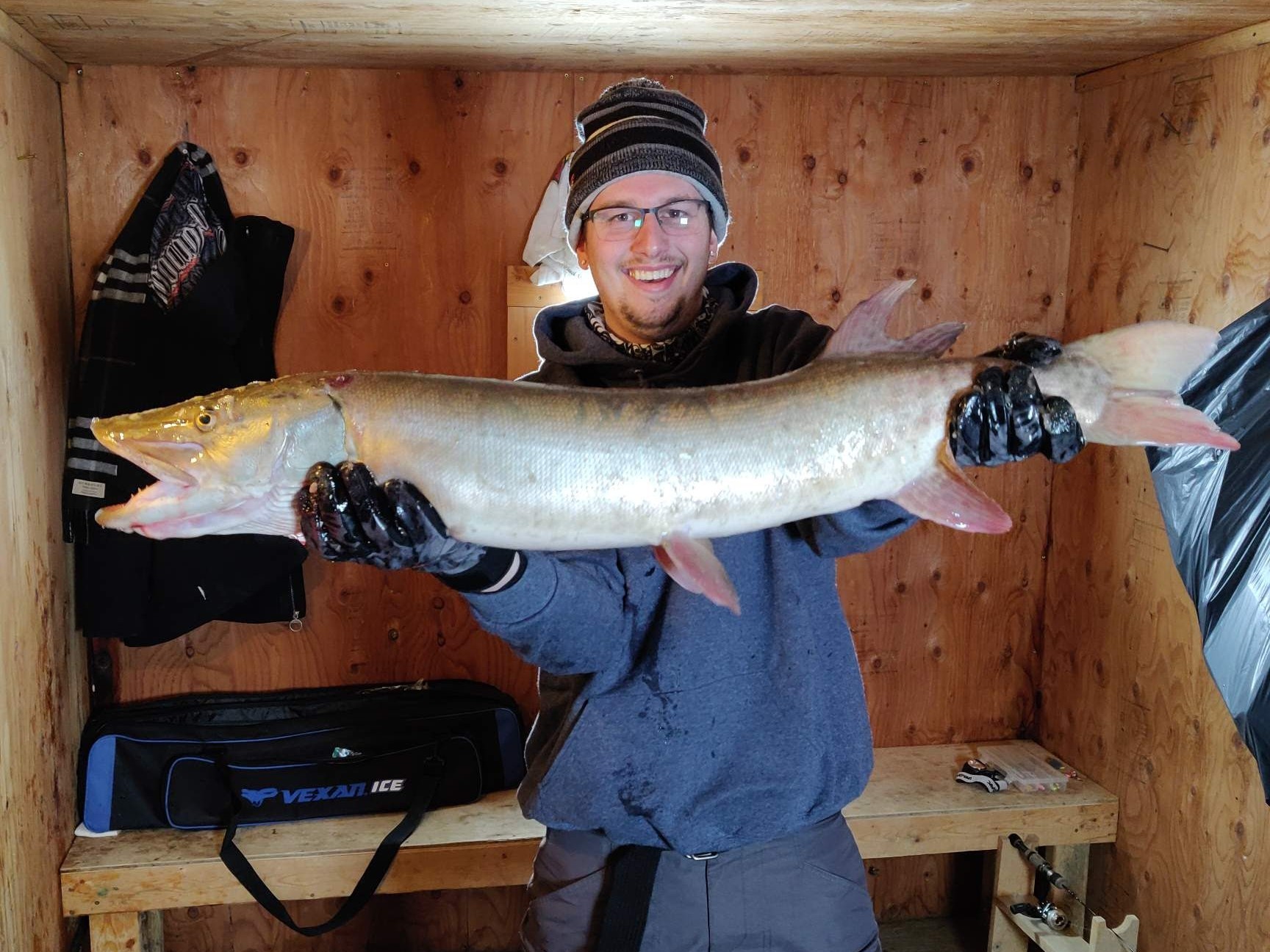 Angler holding a large fish indoors after a successful day on the ice